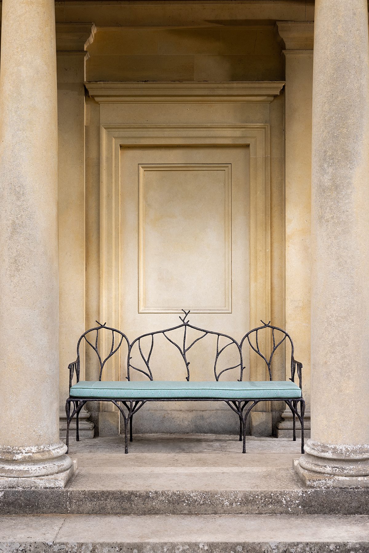 A blue bench in front of a beige stone exterior entrance