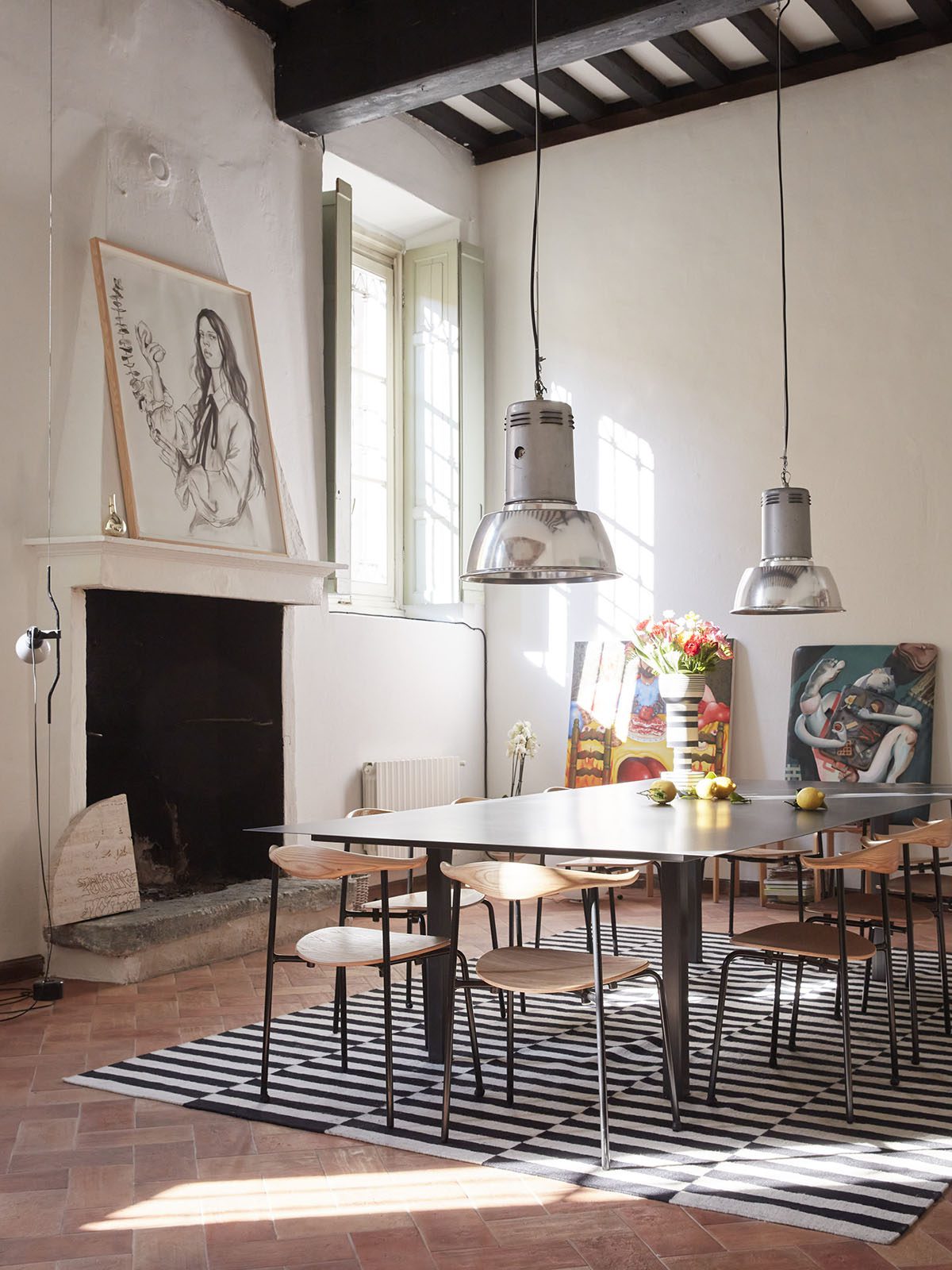 A table and chairs in a room with art leaning on the walls