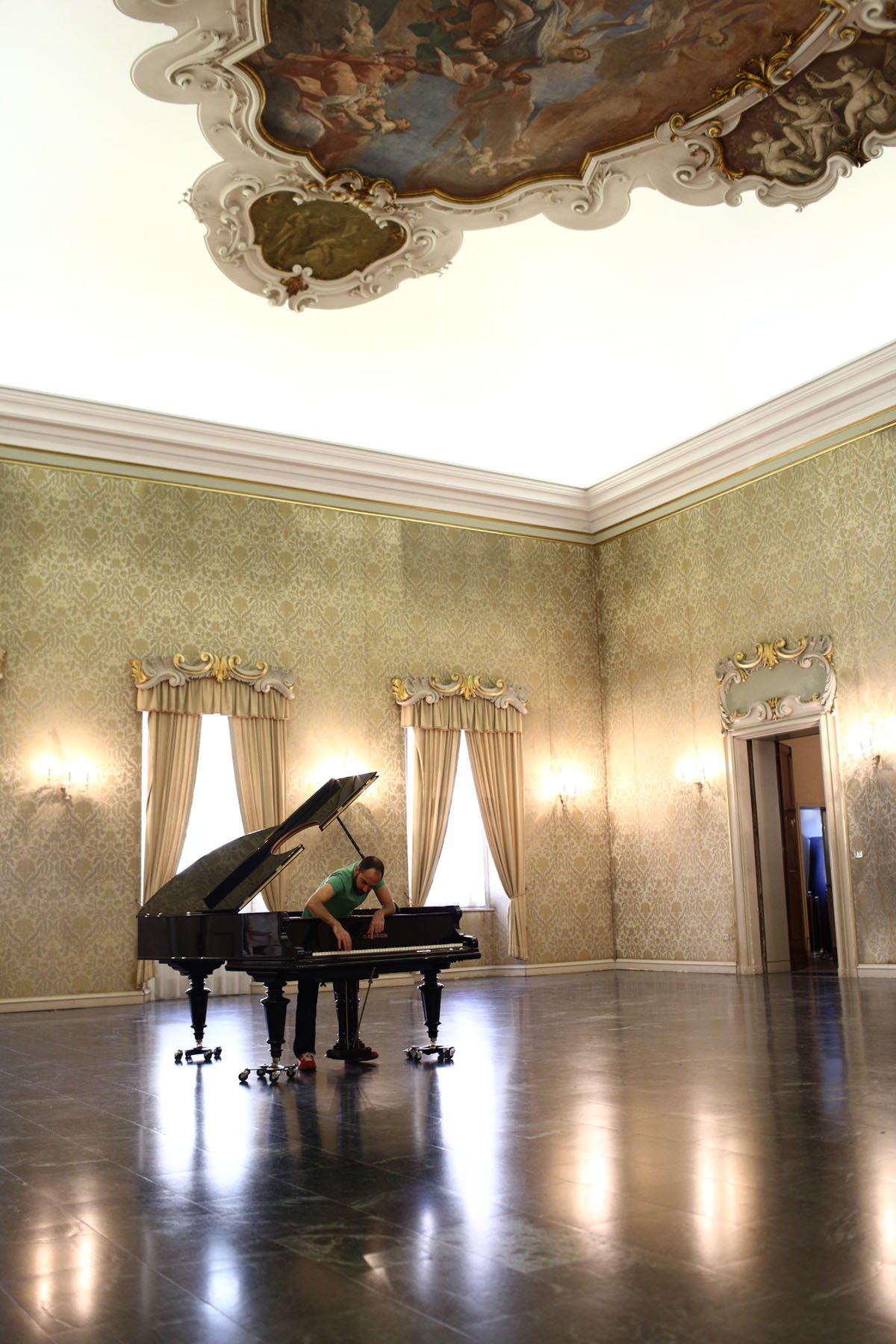 A man working on a grand piano in an old fashioned room