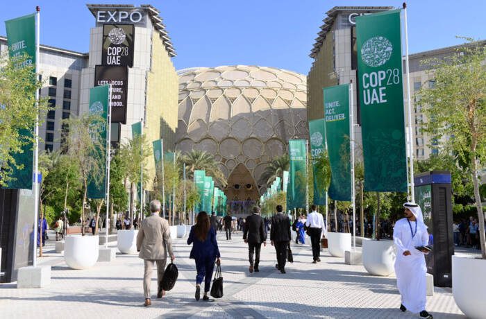People walking in and out of a building that has signs to COP28