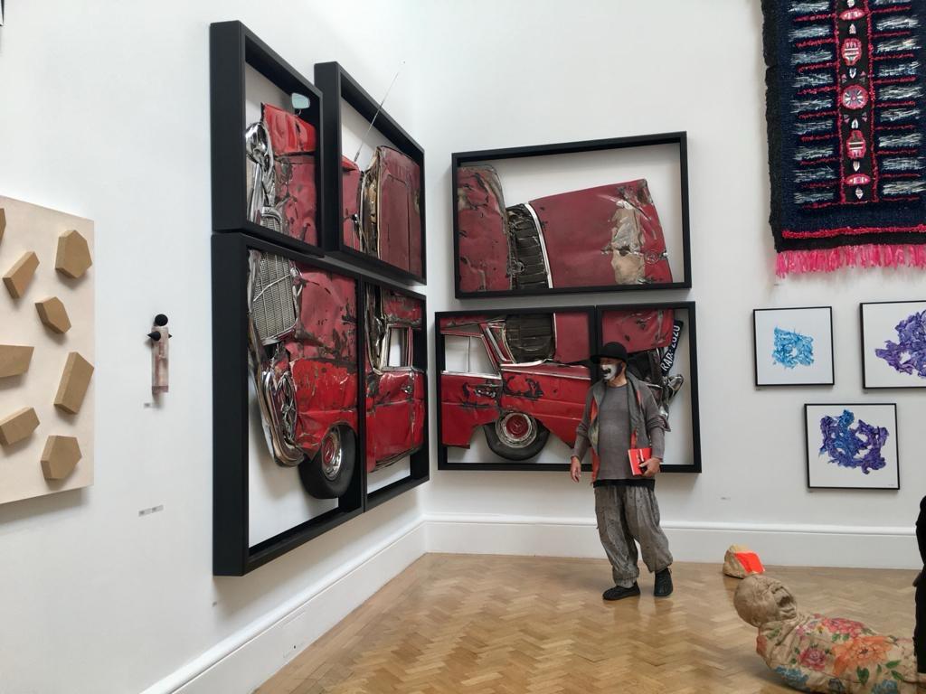 Man in a mask standing next to frames of a crushed car