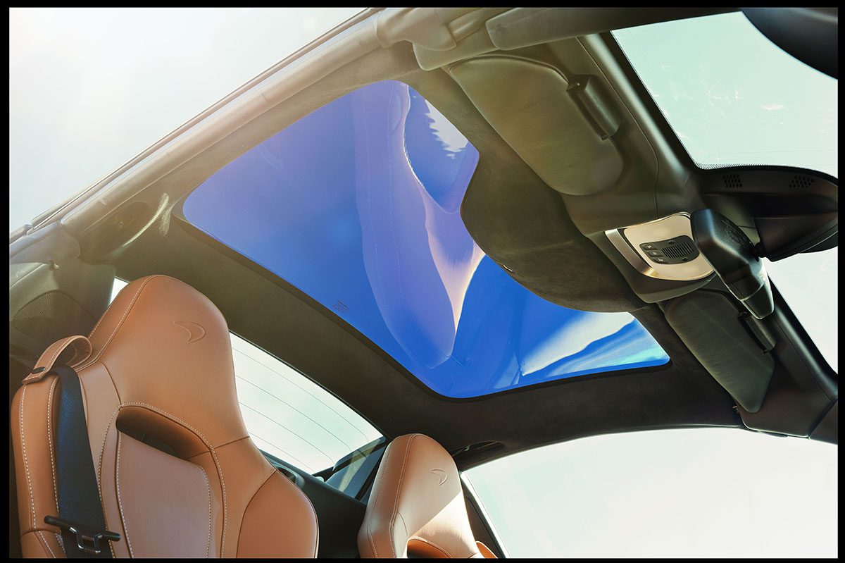 brown leather seats in a car with a window above the seats to see the sky