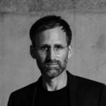 A man wearing a black top and blazer
