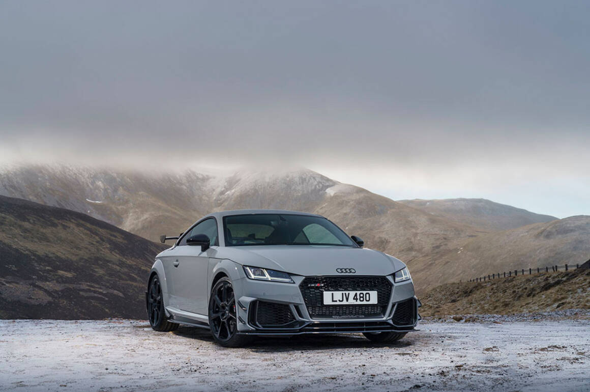 A grey car in the mountains with snow