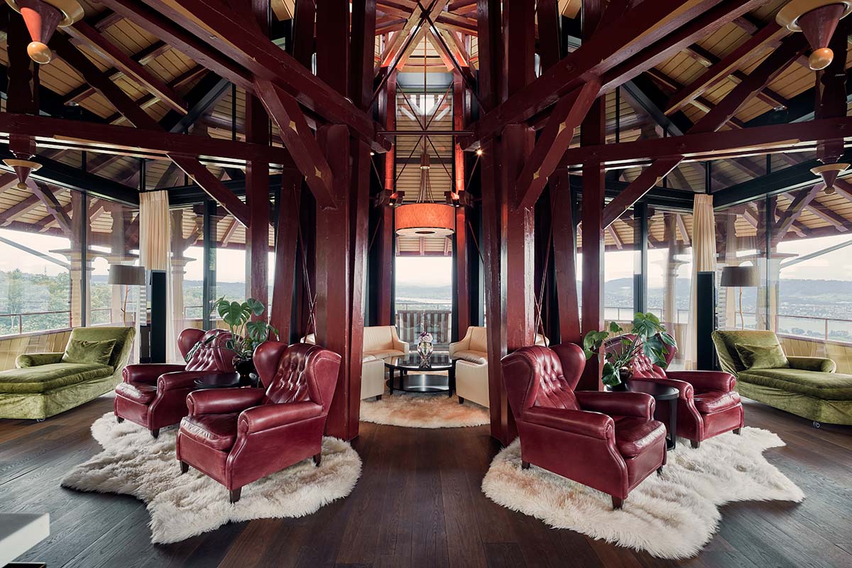 A room with red wooden beams and red leather chairs on white rugs