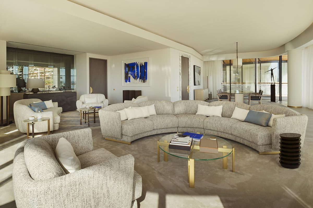 A living room with cream and grey furniture and a blue painting on the wall