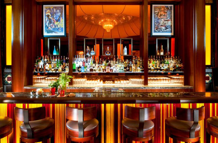 Bar with lots of drinks and lights and chairs and mirror
