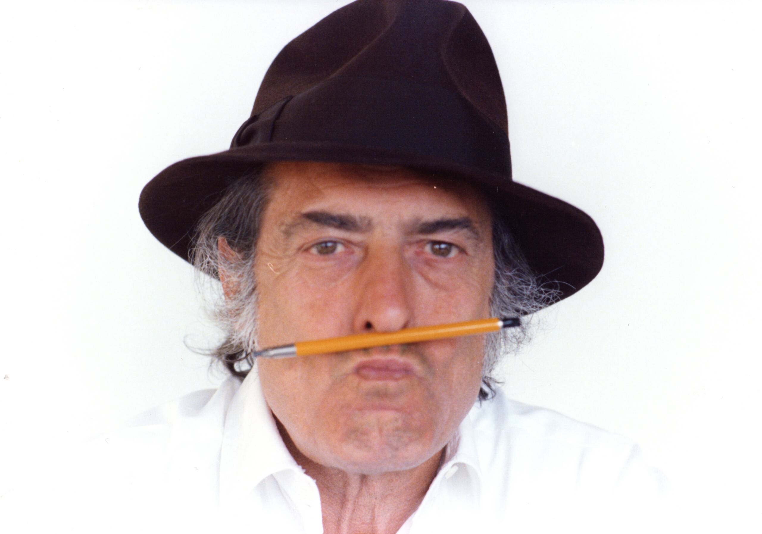 a man with a pencil between his lips and a hat on his head