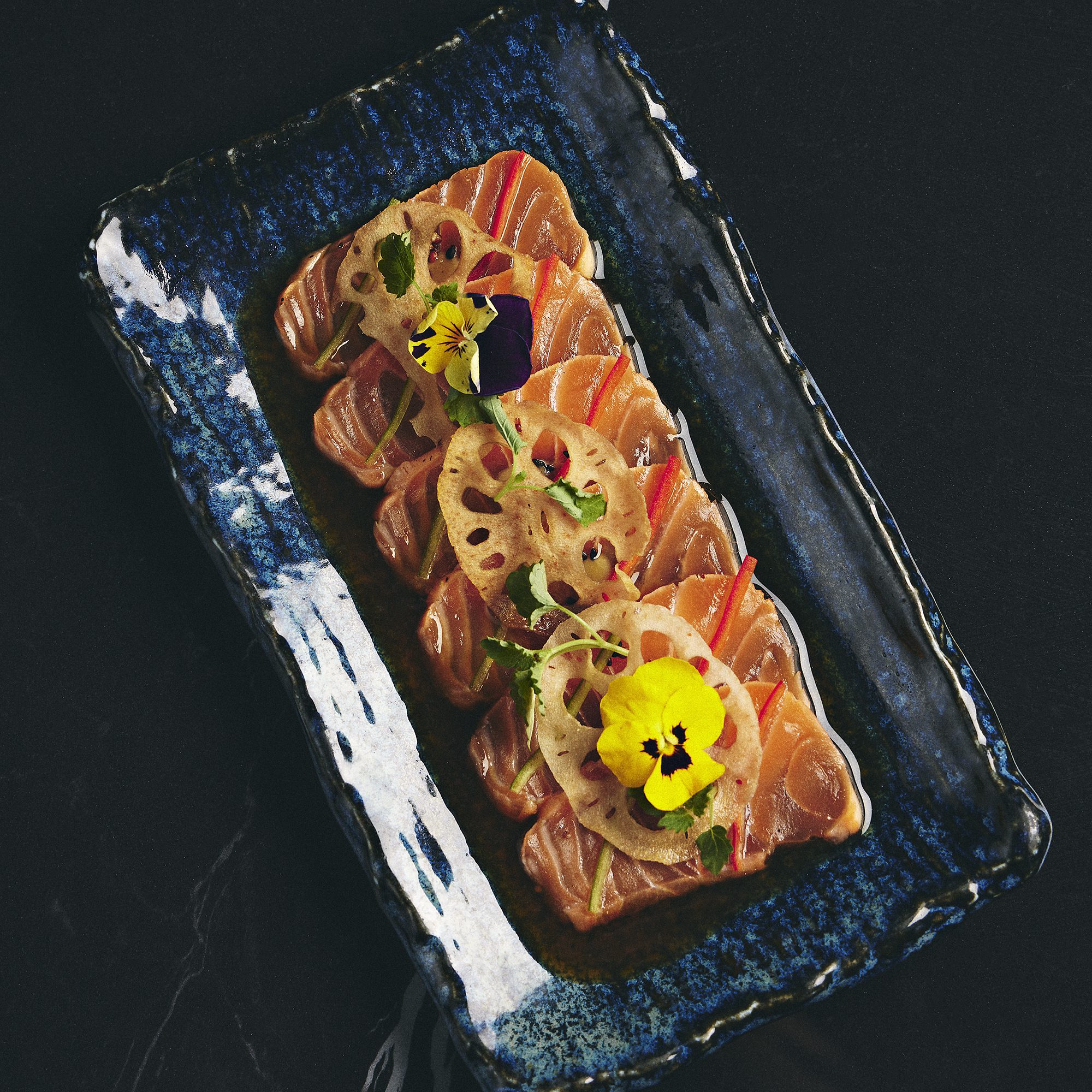 sashimi on a blue plate with flowers