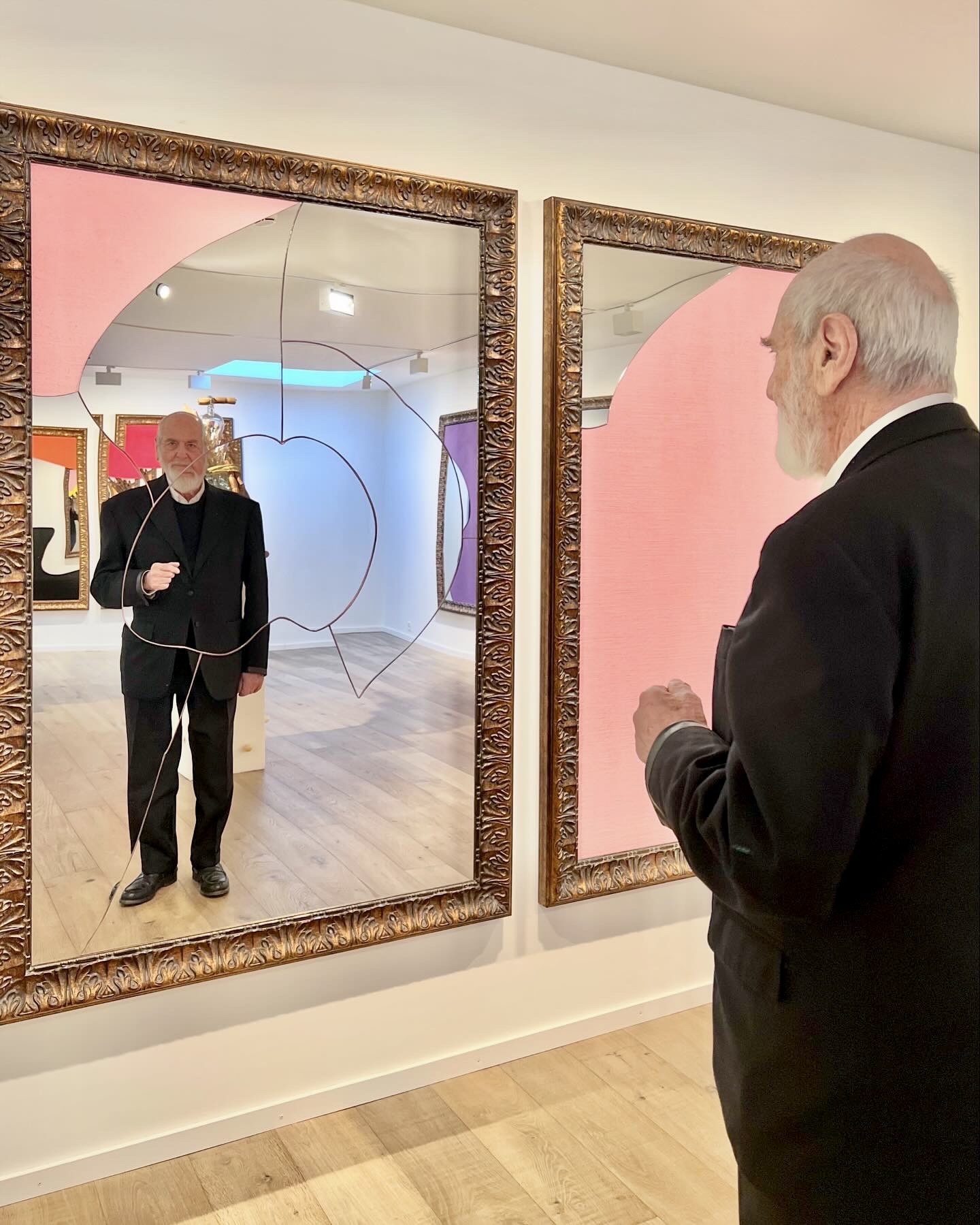 A man looking into a mirror with pink in it