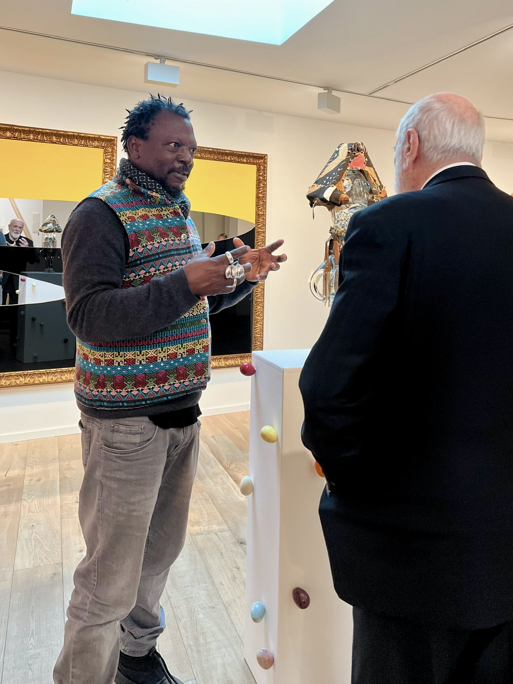 two men stand in a gallery talking