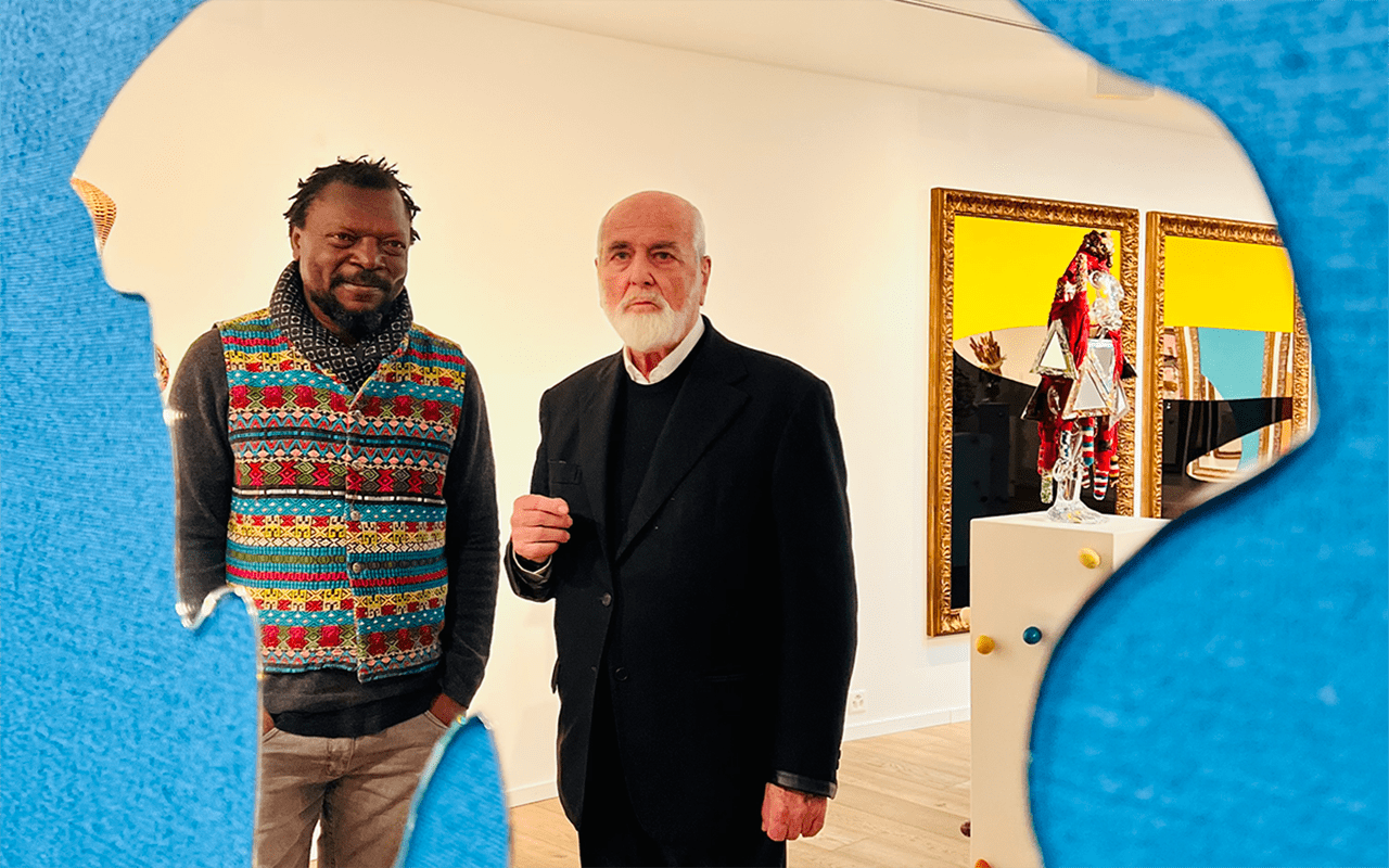 Two artists who are men standing in front of a mirror with a blue background
